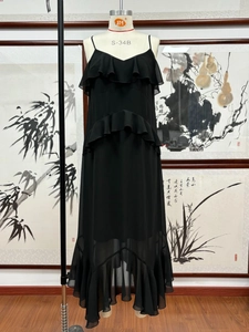 Detail of elegant black chiffon maxi dress with layered ruffles and irregular hem