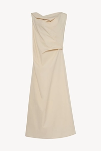 Detail of the asymmetric pleated neckline and draped beige minimalist maxi dress