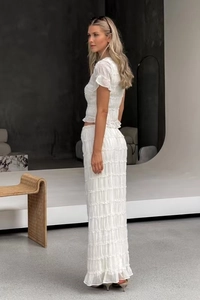 Detailed view of white pleated chiffon fabric texture and ruffled edges on a maxi skirt