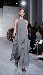 Détail d'une robe longue plissée sans manches grise montrant la coupe chic
