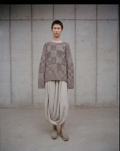 Detail of taupe textured knit sweater with drop shoulder and beige draped long skirt