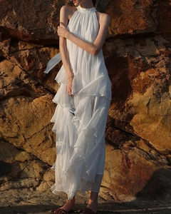 Detailed ruffled layers of a white halter neck maxi dress during golden hour sunlight