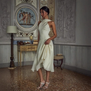Elegant cream satin halter midi dress with an asymmetrical hem in a vintage room