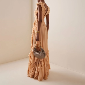 Elegant deep V backless maxi dress with ruffled tiers and a stylish ring handle handbag