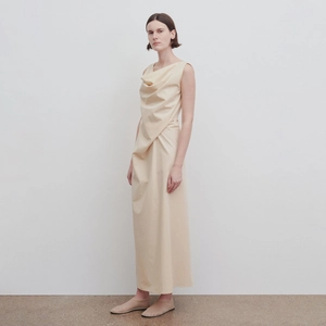 Minimalist beige sleeveless dress with draped cowl neckline and flowing long silhouette
