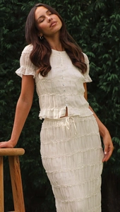 Detailed view of the ruffle edges and pleated chiffon texture on a beige maxi skirt set