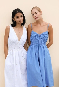 Detail of white embroidered eyelet dress and blue strappy dress with ruffle neckline