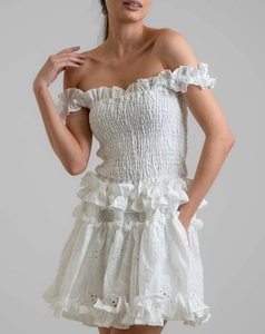 Detailed close-up of white off-shoulder dress with embroidery and ruffled edges