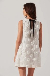 Detail of white mini dress featuring 3D floral textures and a black ribbon bow on back