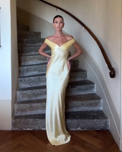 Detail of the elegant pale yellow satin off-the-shoulder evening dress on stone stairs