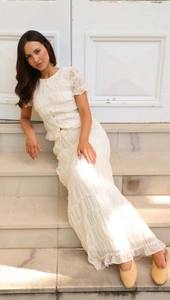 Close-up of cream pleated two-piece set featuring ruffled chiffon long skirt and button-up top