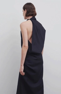 Detail of elegant black backless midi dress with draped halter neck and clean silhouette