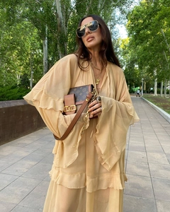 Detailed view of layered chiffon ruffle dress and a designer chain bag on a sunny path