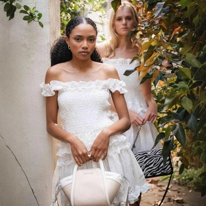 White off-shoulder tiered mini dress with embroidery and a stylish woven handbag
