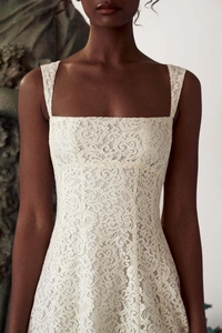 Détail de l'encolure carrée et de la dentelle florale sur la robe blanche élégante