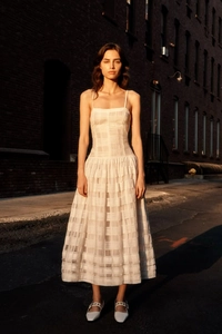 Détail d'une robe midi blanche montrant la texture à carreaux et la coupe ajustée