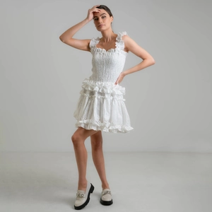 White off-shoulder mini dress with tiered ruffle skirt and intricate floral embroidery