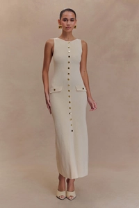 Details der ärmellosen Strickkleid-Textur mit eleganten Goldknöpfen und Rippenmuster