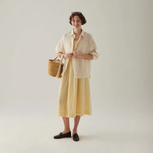 Gelbes Maxikleid im französischen Stil mit creme Hemd und Stroh-Tasche im Sommer-Look