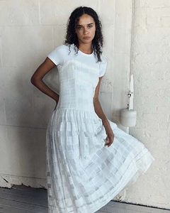 Détail d'une robe blanche à carreaux, texture plissée, silhouette en A avec t-shirt blanc