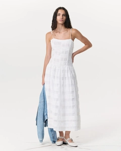 Détail de la robe longue blanche montrant le motif à carreaux et la taille ajustée