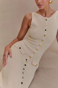 Detailaufnahme des cremefarbenen Strickkleides mit Goldknöpfen und dekorativen Taschen