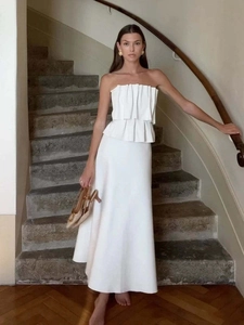 Detail of white strapless two-piece set featuring 3D pleated top and elegant long maxi skirt
