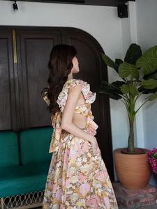 Detail of floral backless maxi dress featuring side cut-outs and layered ruffle shoulders