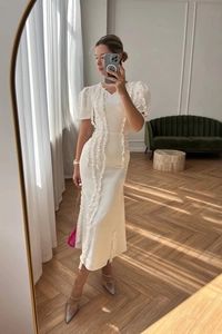 Detail of white V-neck midi dress featuring puff sleeves and vertical ruffle trim accents