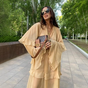 Boho beige deep V-neck maxi dress with ruffled layers and flared sleeves in a sunny garden