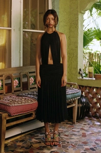 Detail of black halter midi dress with waist cut-out and pleated texture in a resort setting