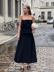 Detail of elegant black strapless evening gown with layered ruffle bust and flowing long skirt