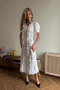 Close-up of elegant white dress featuring vertical ruffles and puffed short sleeves