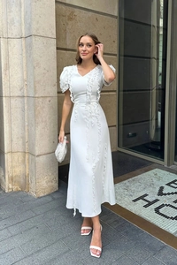 Elegant white V-neck midi dress with puff sleeves and ruffled front detail on city street