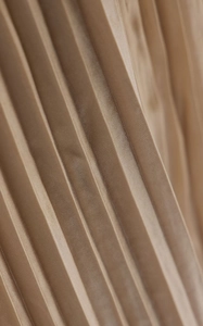 Detail of pleated champagne satin fabric with subtle metallic luster and elegant drape