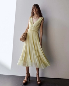 Détail d'une robe de soirée jaune avec col en V, nœuds à la taille et ourlet en dentelle