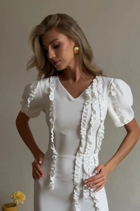 Detail view of white evening dress with elegant ruffled trim and puff sleeves
