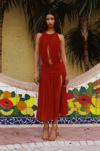Detail of red halter cutout dress featuring pleated chiffon and a high slit side view