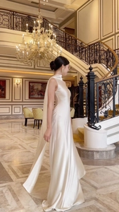 Elegant pearl white satin evening gown featuring a halter neck and long draped cape detail