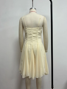 Detail of light beige chiffon dress with delicate straps and a pleated texture