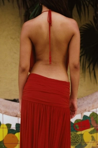 Detailed back view of a red backless halter dress featuring elegant pleated waist details