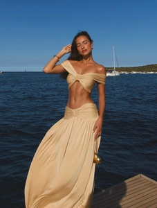 Detail of light beige beach set featuring a pleated crop top and high waist draped long skirt