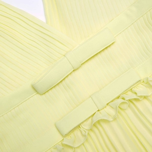 Détail de tissu plissé jaune clair avec nœuds décoratifs et bordure à volants élégante