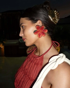 Detail of gradient red fabric flower earrings and golden fan-shaped hair clip on a model