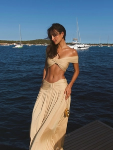 Detail view of twist-knot waist and silk-like draped fabric on a beige maxi skirt