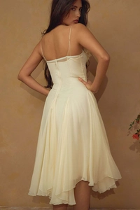 Detailed back view of a cream evening dress featuring thin straps and flowing wavy hemline
