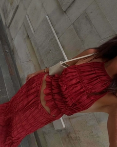 Detail of red pleated two-piece set featuring backless halter top and tiered ruffle skirt
