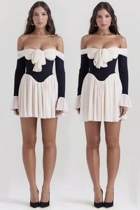 Detail view of contrast backless dress with white bow top and pleated black mini skirt