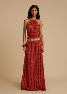 Detail of rust red two-piece set featuring pleated halter top and tiered maxi skirt fabric