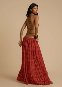 Detail of rust red halter top with backless lace-up design and tiered pleated maxi skirt